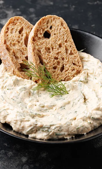 Tranches de pain complet dans un bol de trempette crémeuse aux herbes à Toulouse en Haute-Garonne 31
