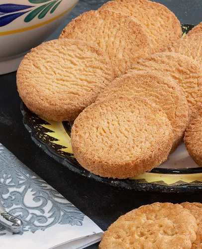 Gros plan de biscuits sablés dorés disposés sur une assiette.