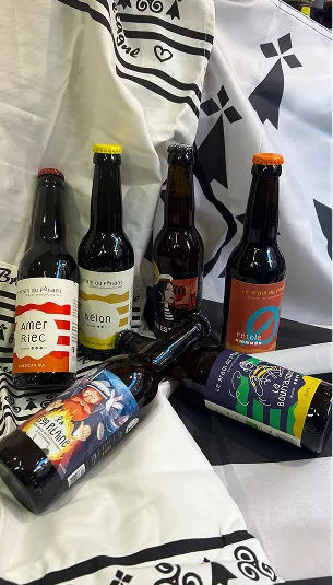 Six bouteilles de bière artisanale avec des étiquettes colorées, sur un drapeau breton à Toulouse en Haute-Garonne 31